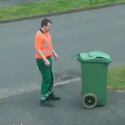 Worker following trash bin